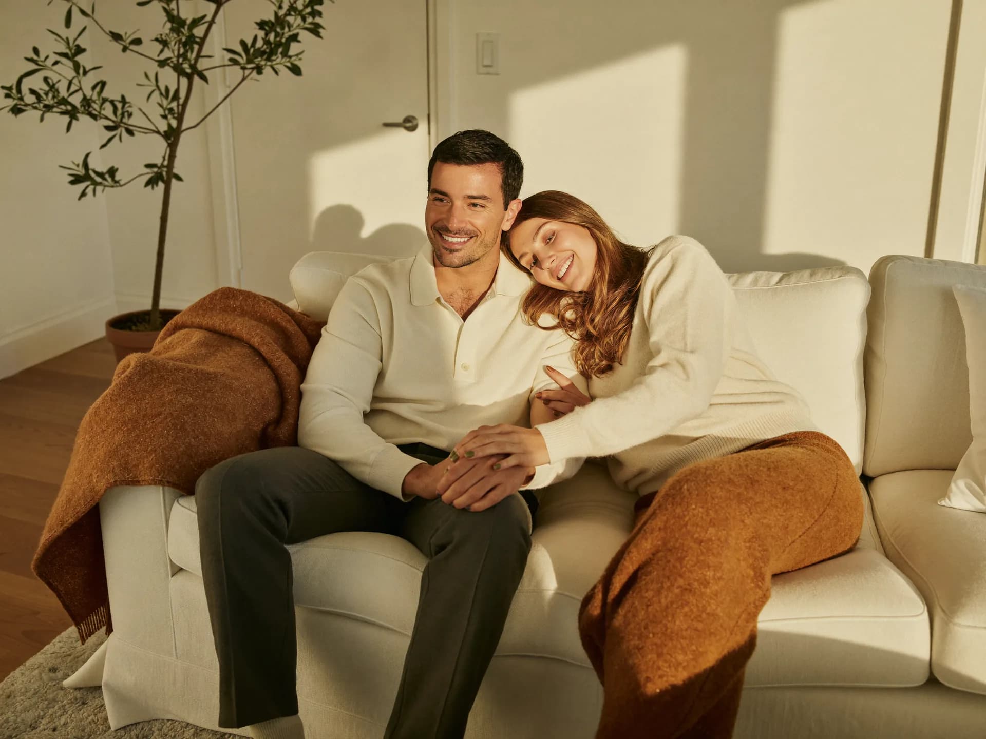A couple sharing a quiet moment on a sunlit couch — connection that a discreet sexual health program supports.