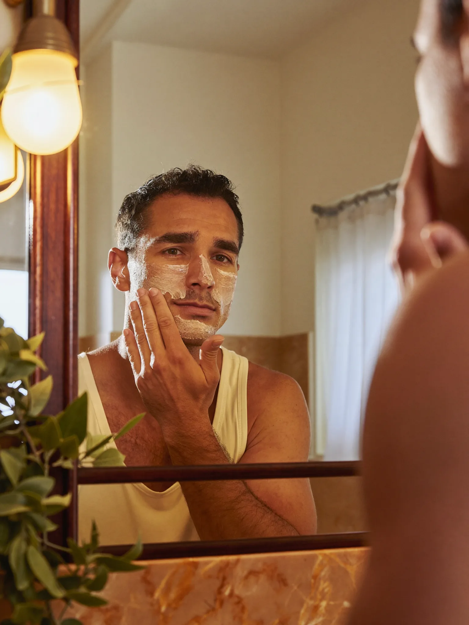 A person looking at their skin in a bathroom mirror during a calm morning skincare routine.