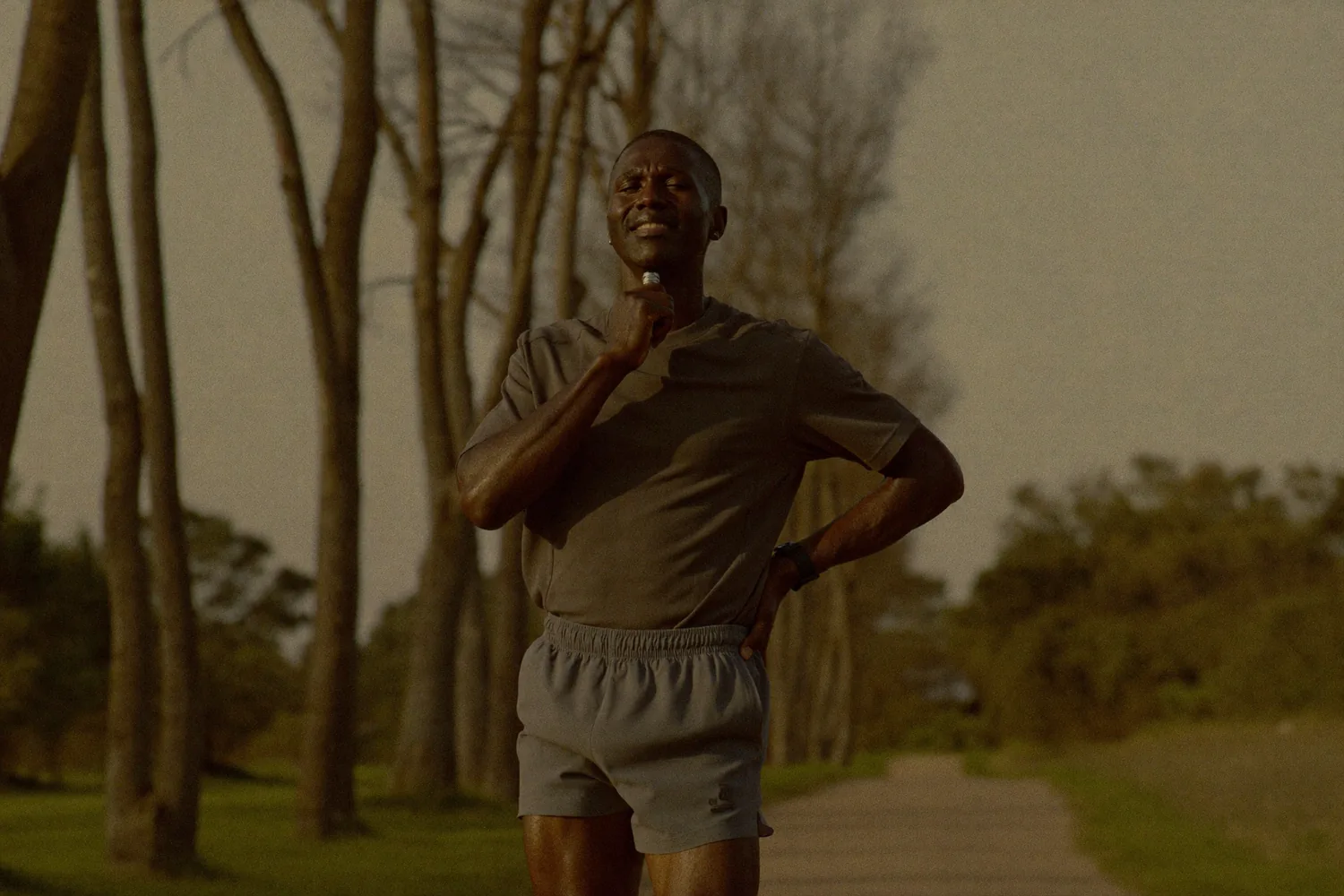 A fit man finishing a morning run on a tree-lined path at golden hour, the long-term, steady-state feel of a NuHealth maintenance phase