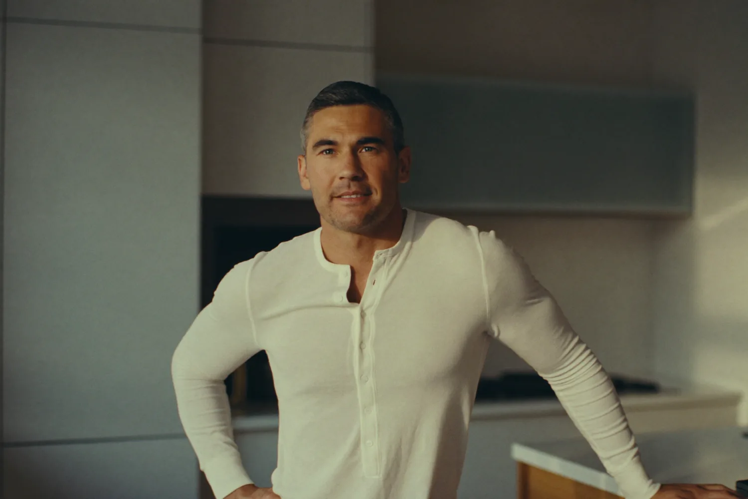 A confident, healthy man in his mid-forties in a bright kitchen on a calm morning, the steady clarity a NuHealth hormone-optimization protocol supports